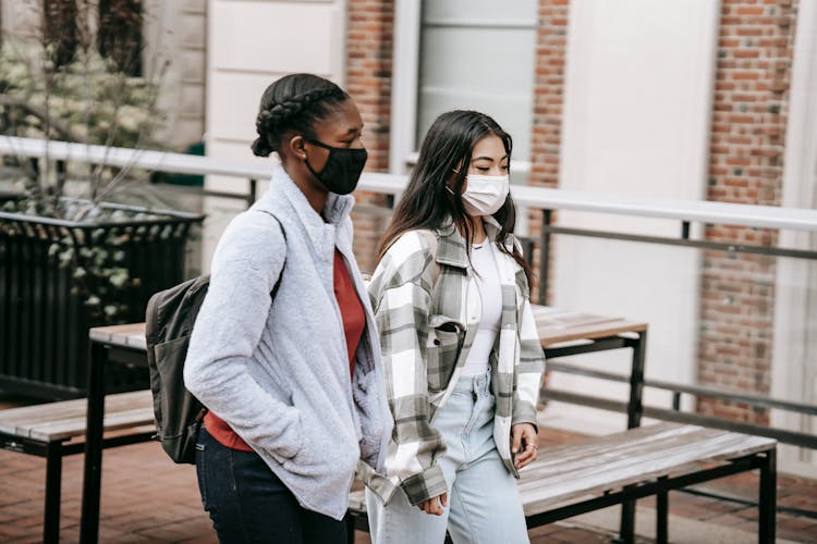 Diverse Students Walking Near Table In Campus