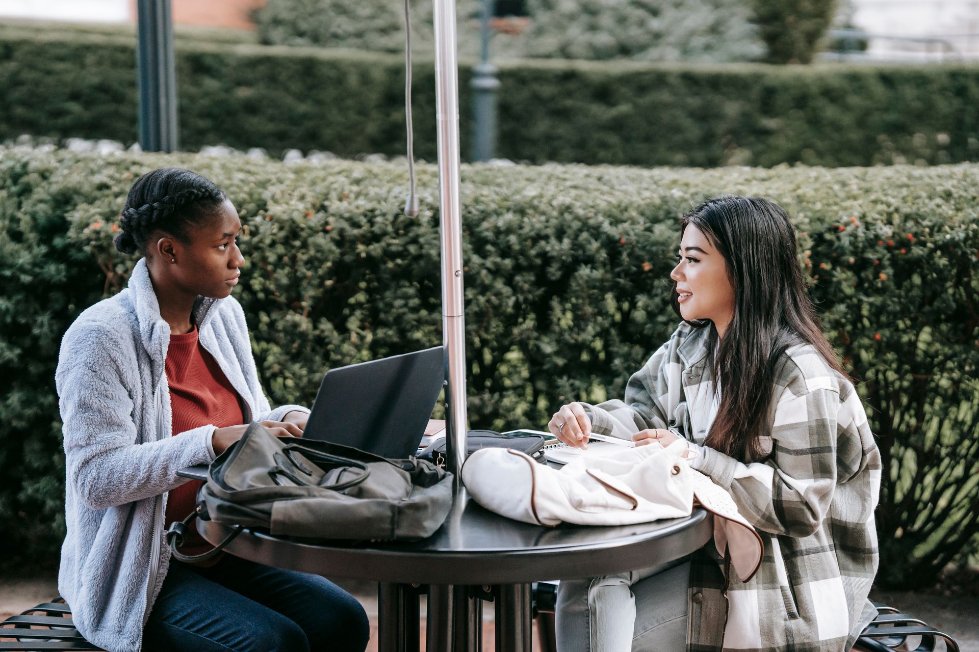 Two students collaborating on a project at an outdoor university campus.