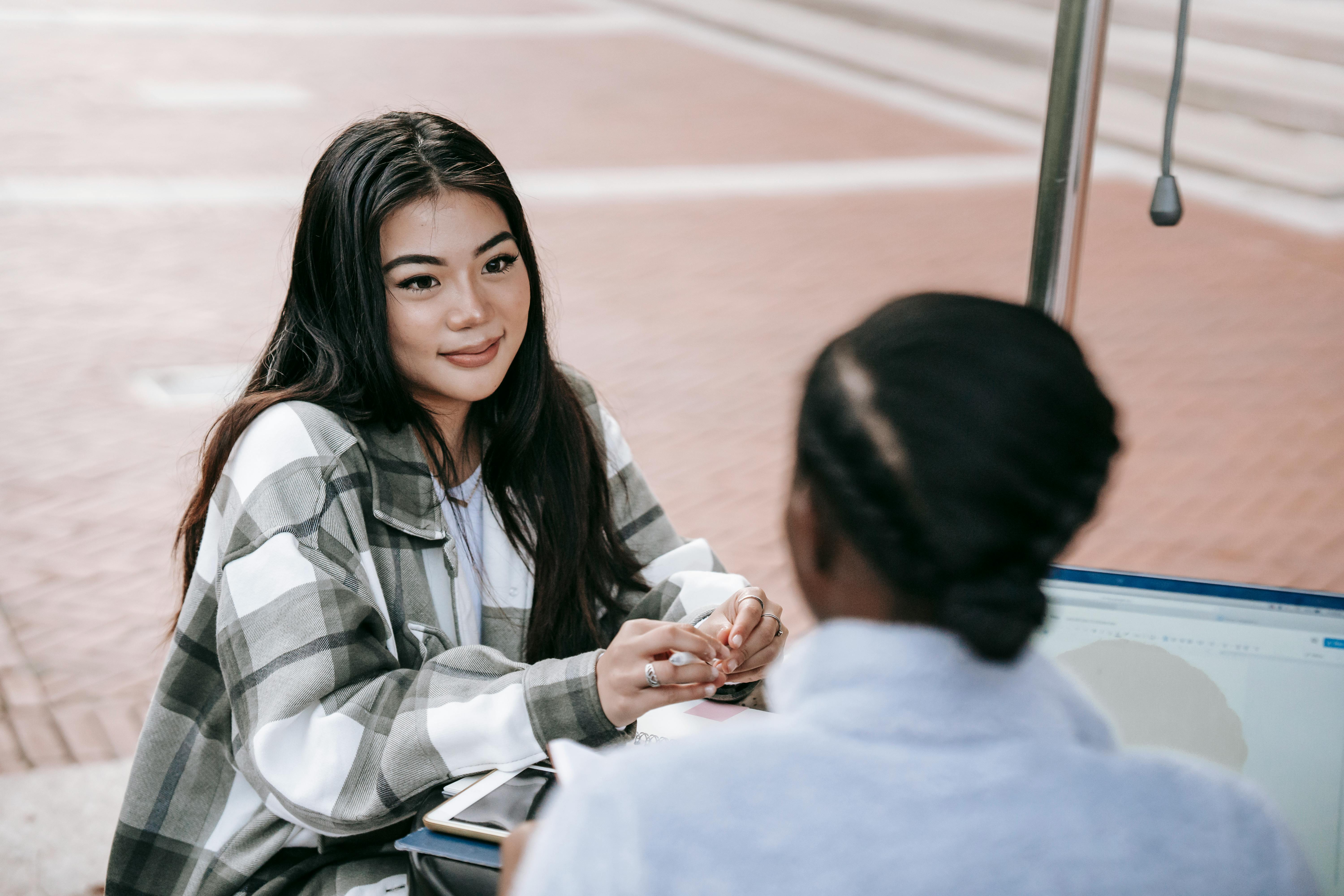 A smiling woman showing a helpful product on her laptop to a friend