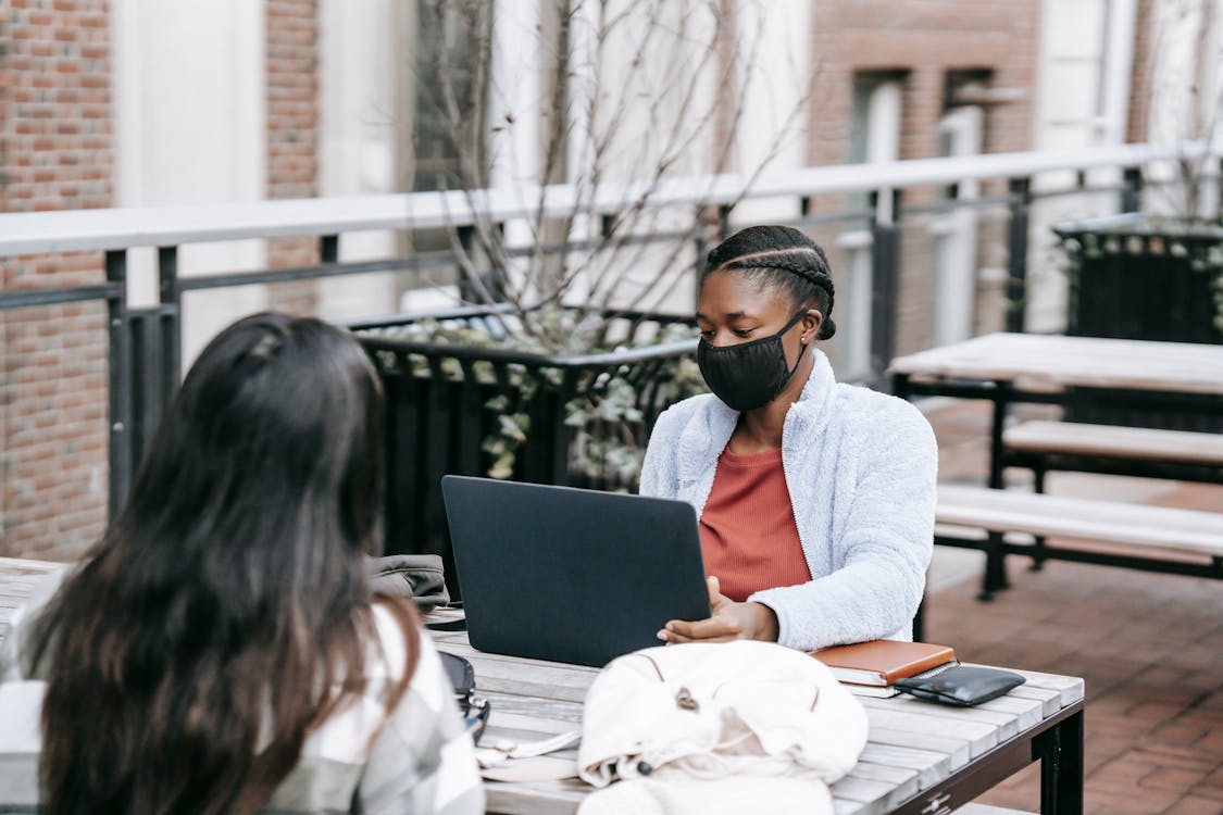 Black woman using laptop doing task with partner