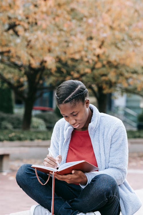 Free Attentive black woman with diary in urban park Stock Photo