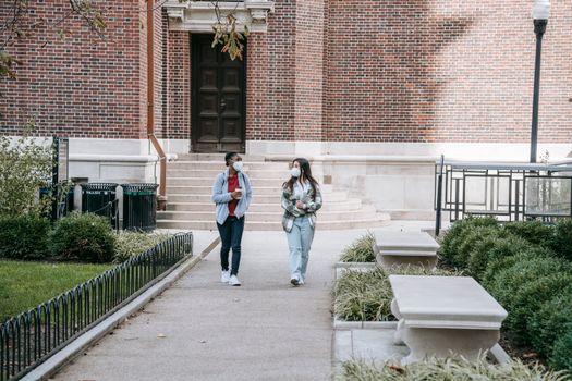 放学后，一位穿着休闲服、戴着医用口罩的年轻多民族女学生在校园公园散步