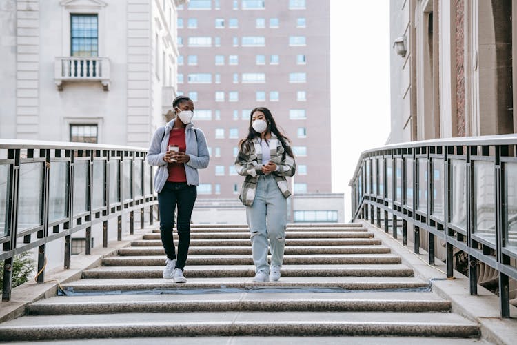 Unrecognizable Multiethnic Young Female Friends Going Downstairs In City Park