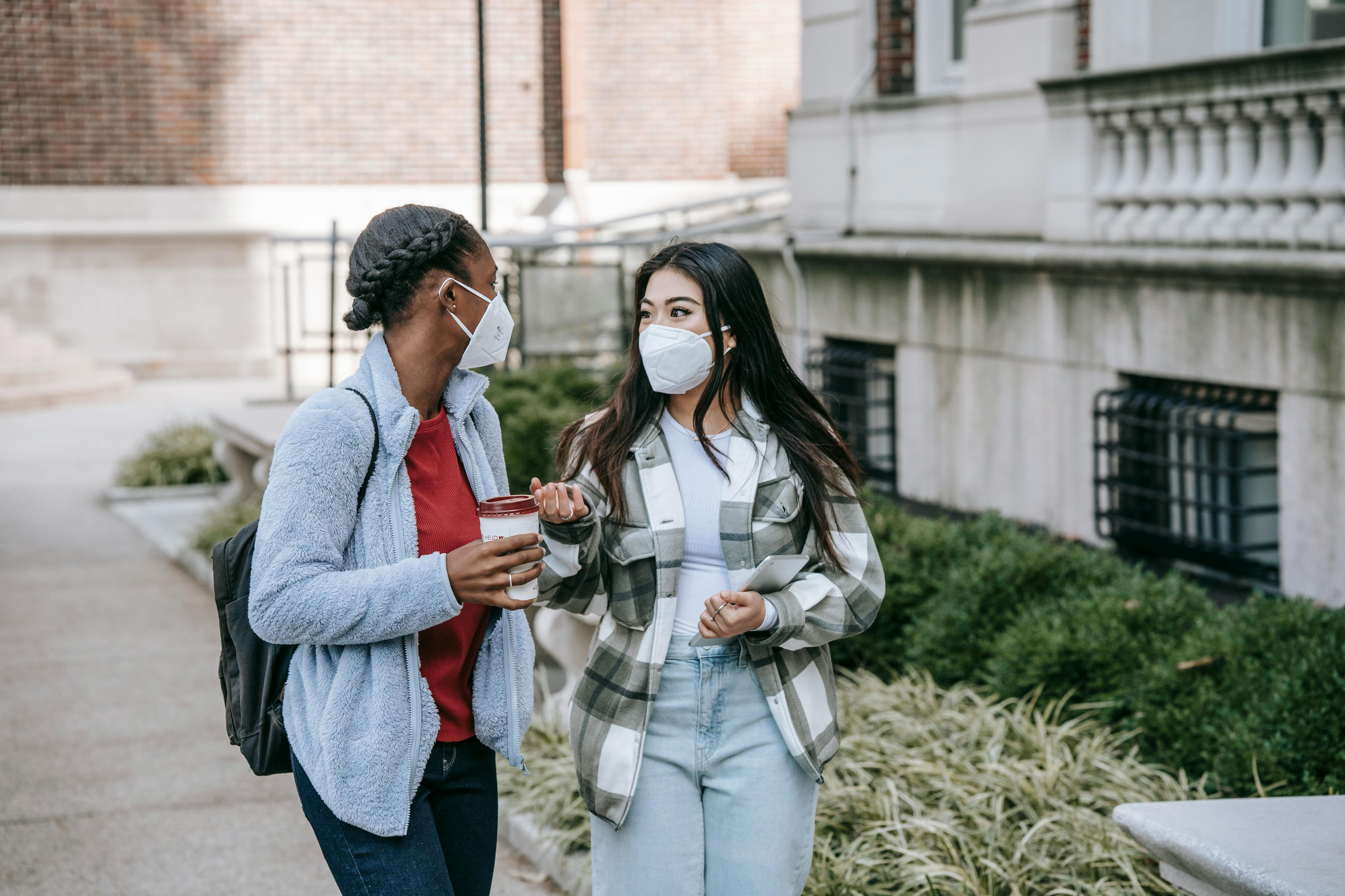 diverse female teens standing near college building and chatting