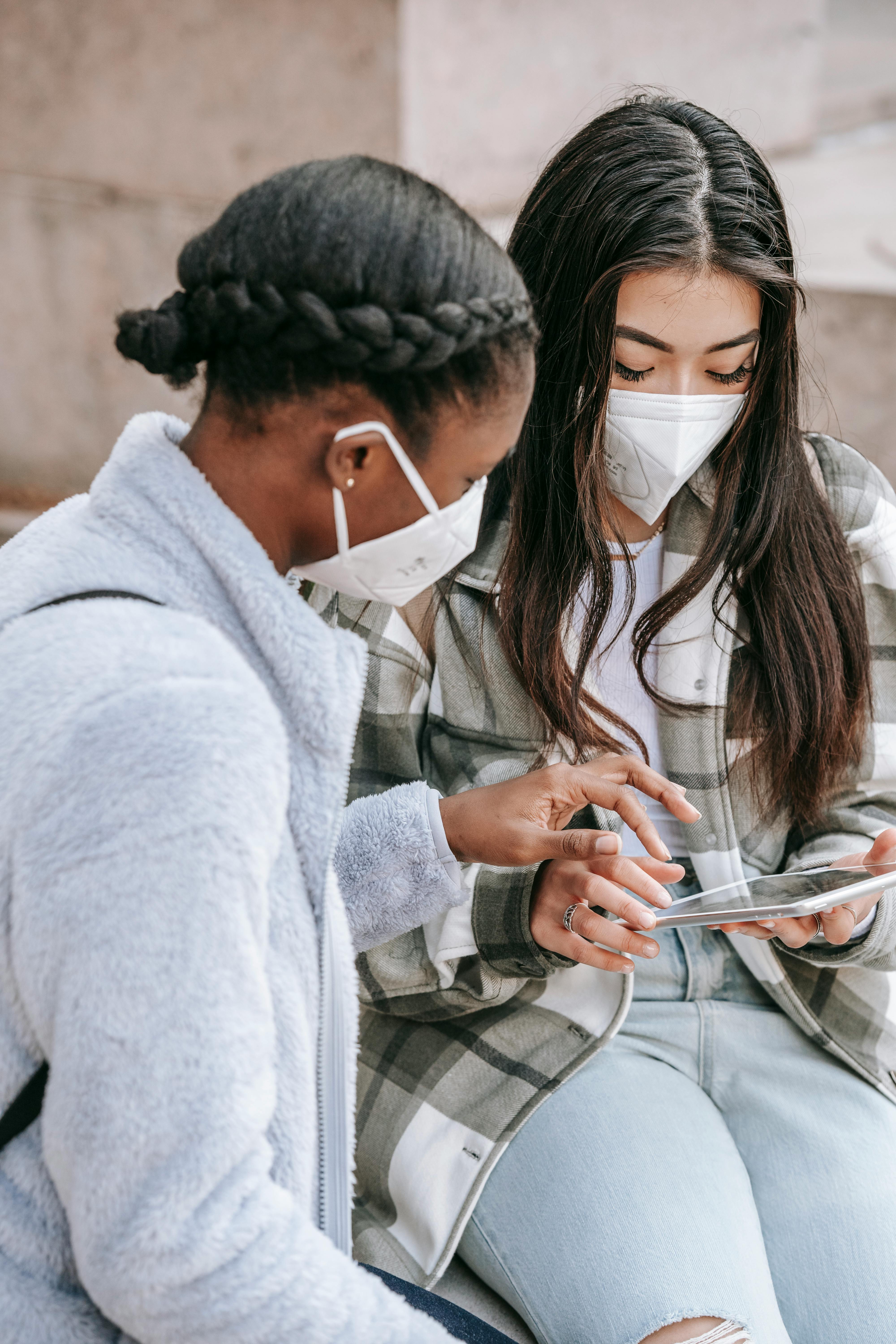 multiracial female students using tablet on city street