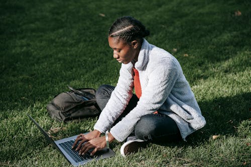 African American lady sitting on grass with netbook