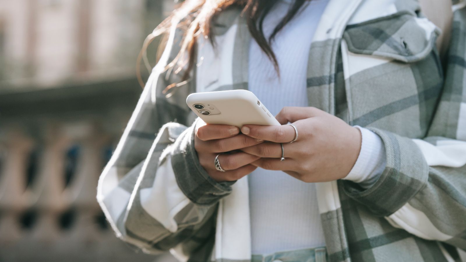 A person checking their phone while walking outside