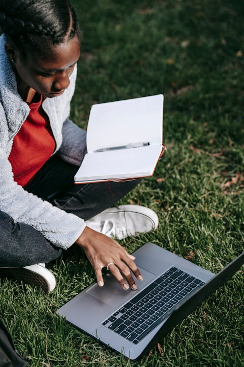 Black woman sitting with netbook on grass