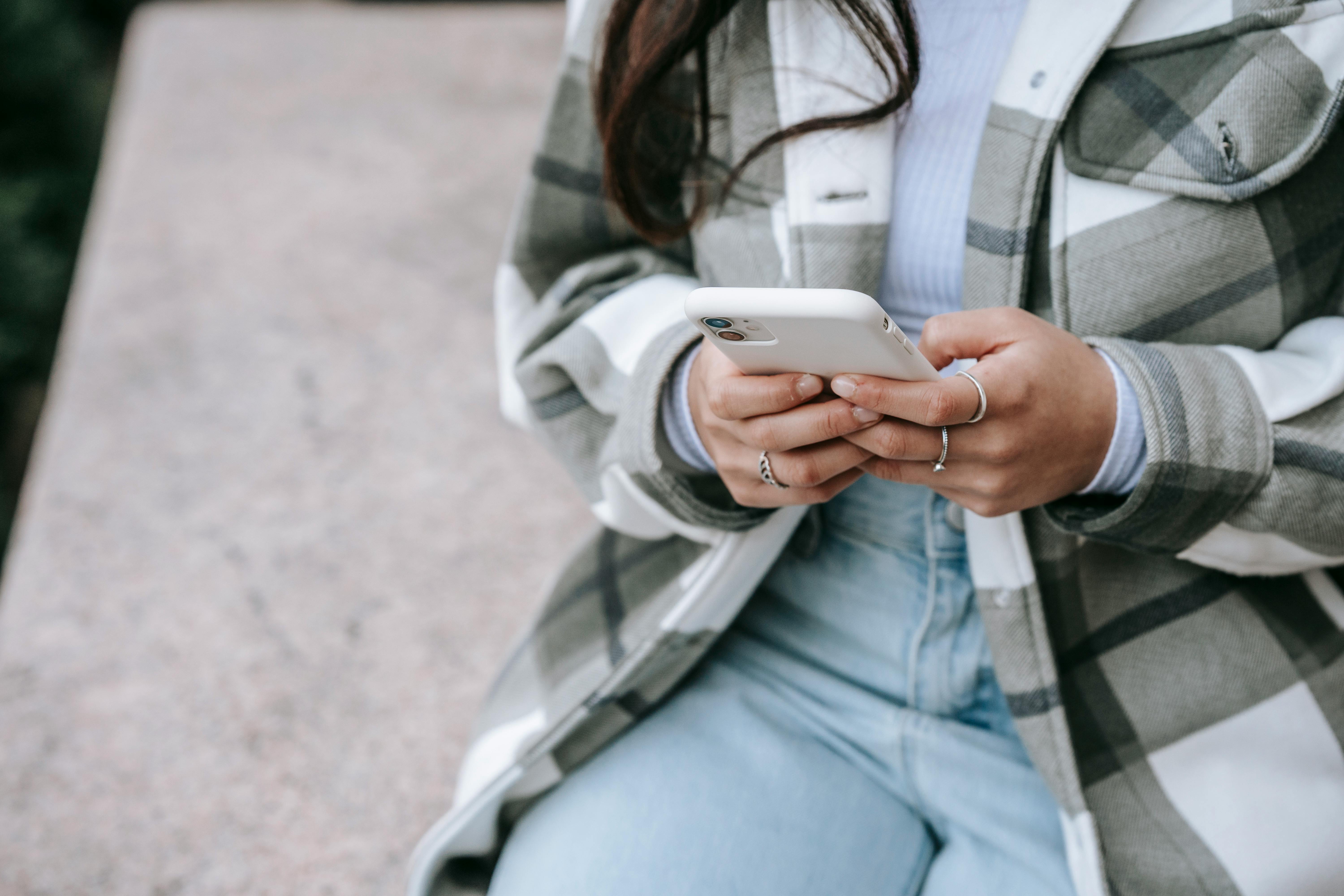 faceless woman sitting in street with phone