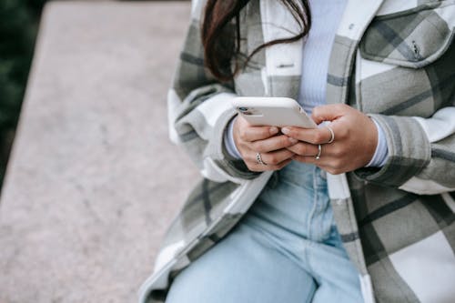 Free Faceless woman sitting in street with phone Stock Photo