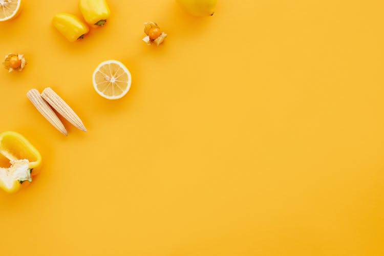 Sliced Lemon And Vegetables On Yellow Surface