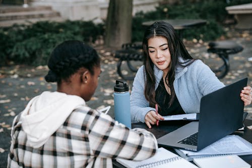 Concentrated diverse students with laptop at table