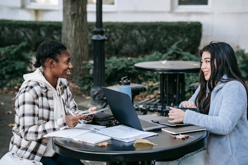 Smiling diverse students with devices at table