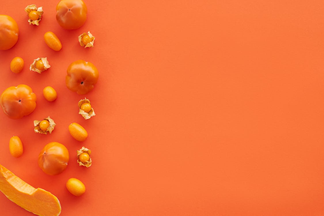 Close-Up Shot of Orange Fruits and Vegetables on an Orange Surface