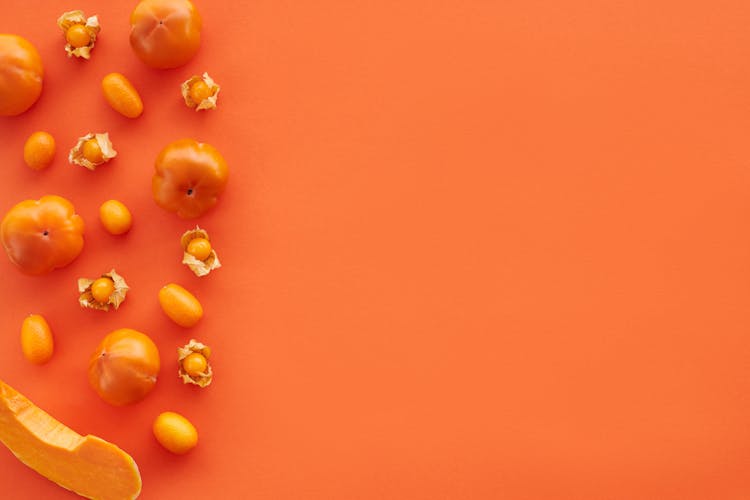 Close-Up Shot Of Orange Fruits And Vegetables On An Orange Surface