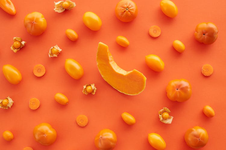 Close-Up Shot Of Orange Fruits And Vegetables On An Orange Surface