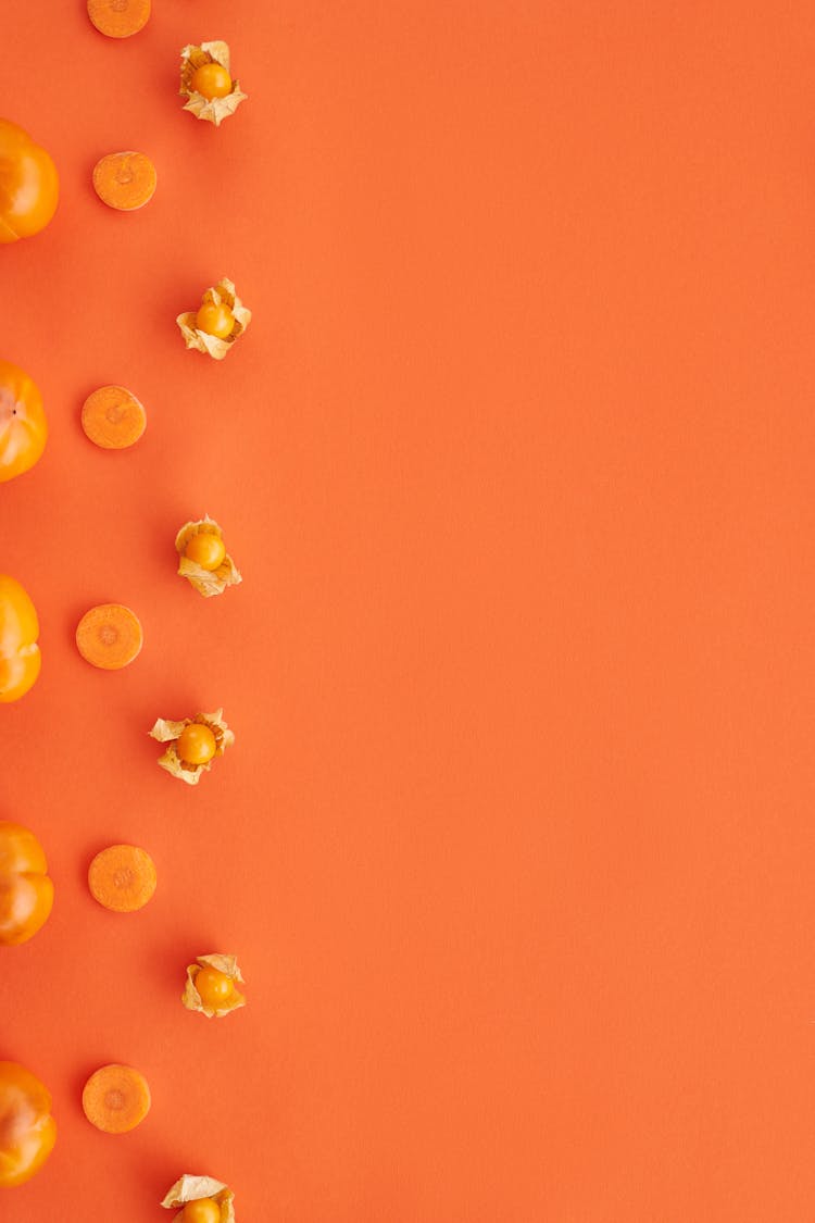 Close-Up Shot Of Orange Fruits And Vegetables On An Orange Surface