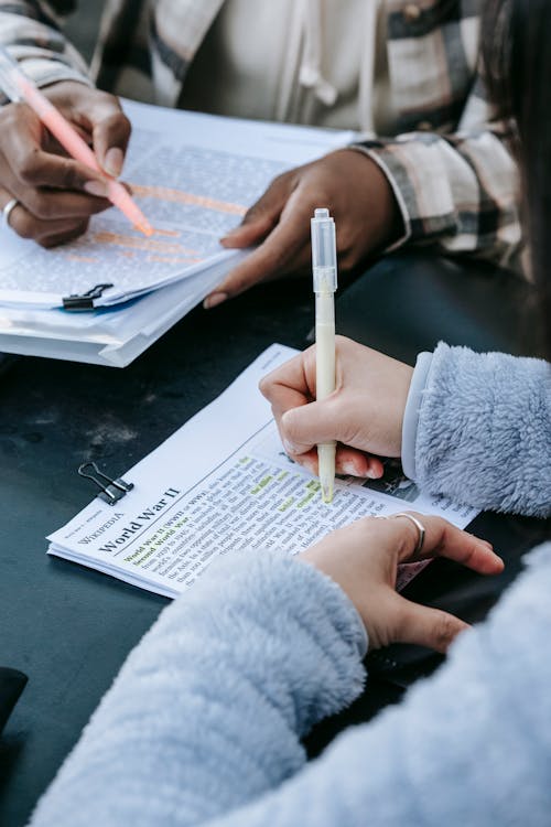 Crop unrecognizable diverse women doing paperwork together