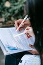 Crop faceless multiracial women reading documents together in park