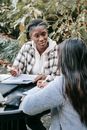 Positive multiethnic female students working on assignment in park