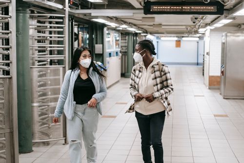 Free Multiracial women in protective masks walking together in hallway of subway and looking at each other Stock Photo