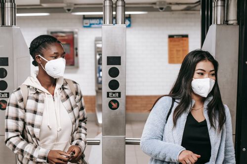 Free Multiethnic girlfriends in casual wear and protective masks entering metro station during coronavirus epidemic Stock Photo
