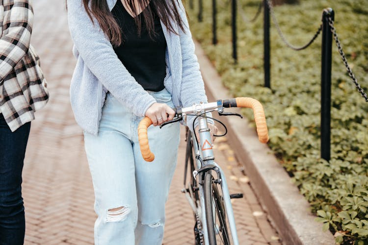 Woman With Bicycle Walking With Friend In Park