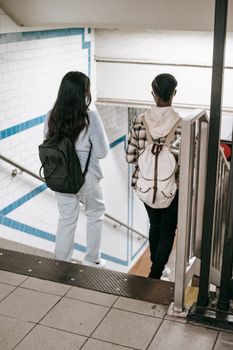 两名年轻女子背着背包走下地铁楼梯，拥抱城市生活