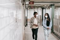 Multiracial women in protective masks walking in passage of underground during coronavirus epidemic and looking at each other