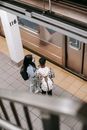 From above back view of unrecognizable black female student with girlfriend in mask in subway against public transport