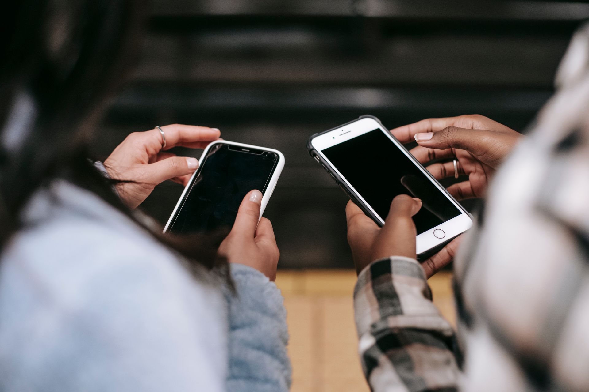 Two women holding smartphones, engaged in social media browsing.