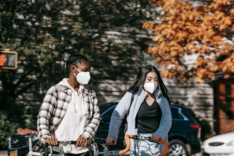 Anonymous Diverse Girlfriends With Bikes On City Street In Fall