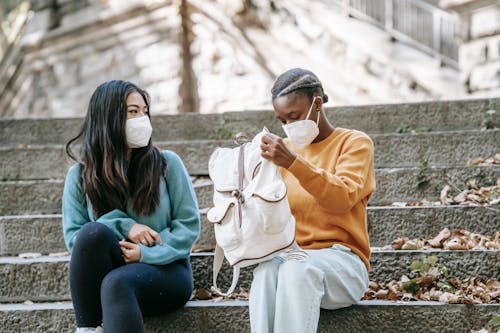 Unrecognizable multiethnic students in masks on city stairs