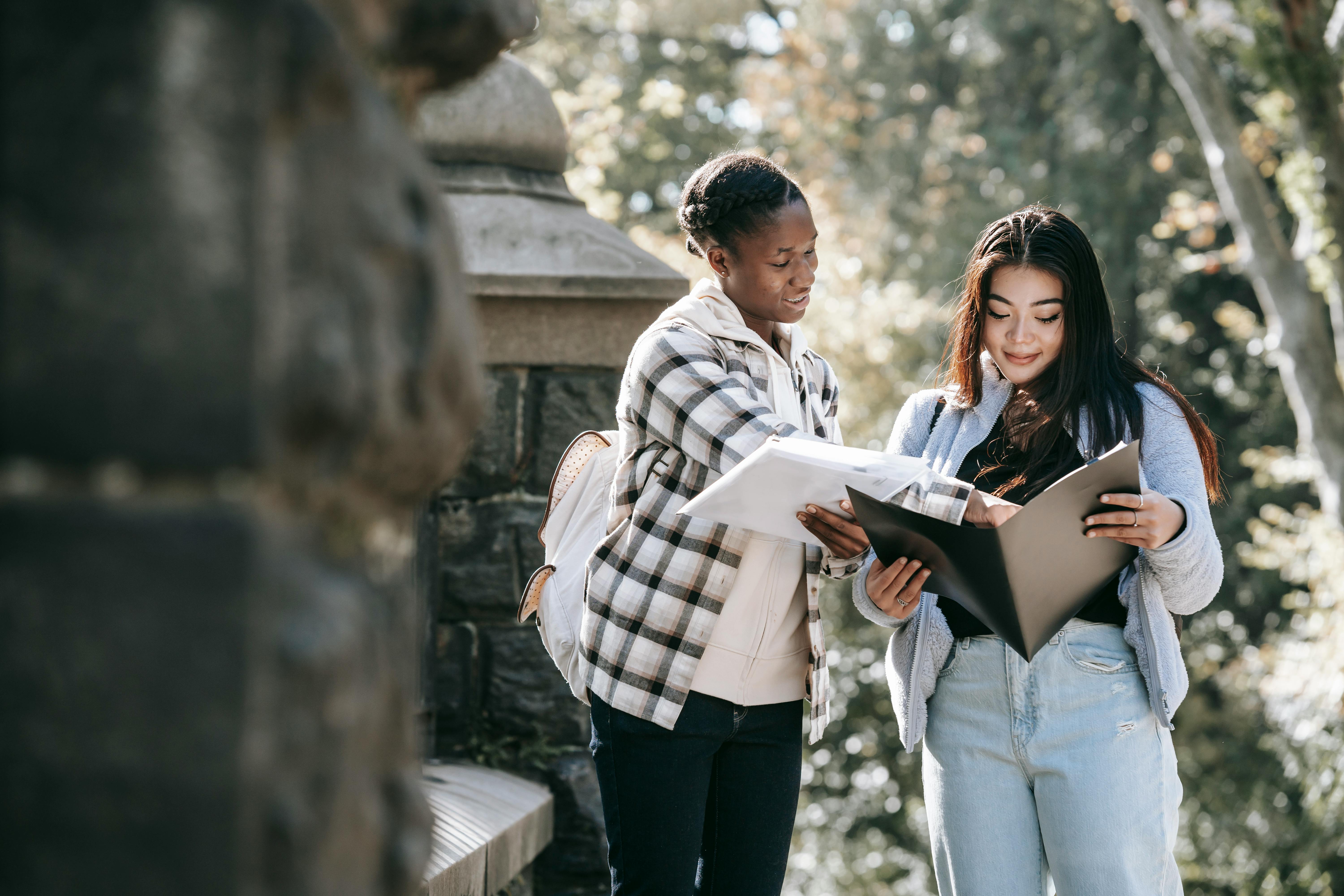 black woman explaining homework to asian girlfriend in town