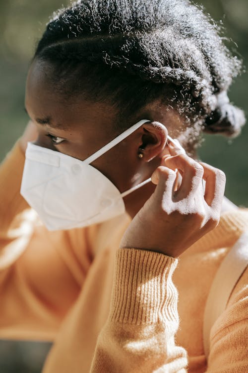 Crop black woman putting on face mask in park