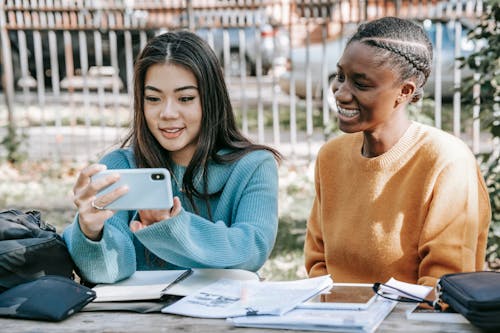 Glad multiethnic women making video call with smartphone