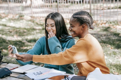 Multiethnic young women talking online in video chat on street