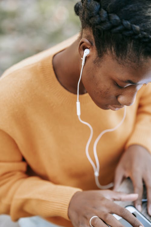 Black woman in earphones scrolling smartphone