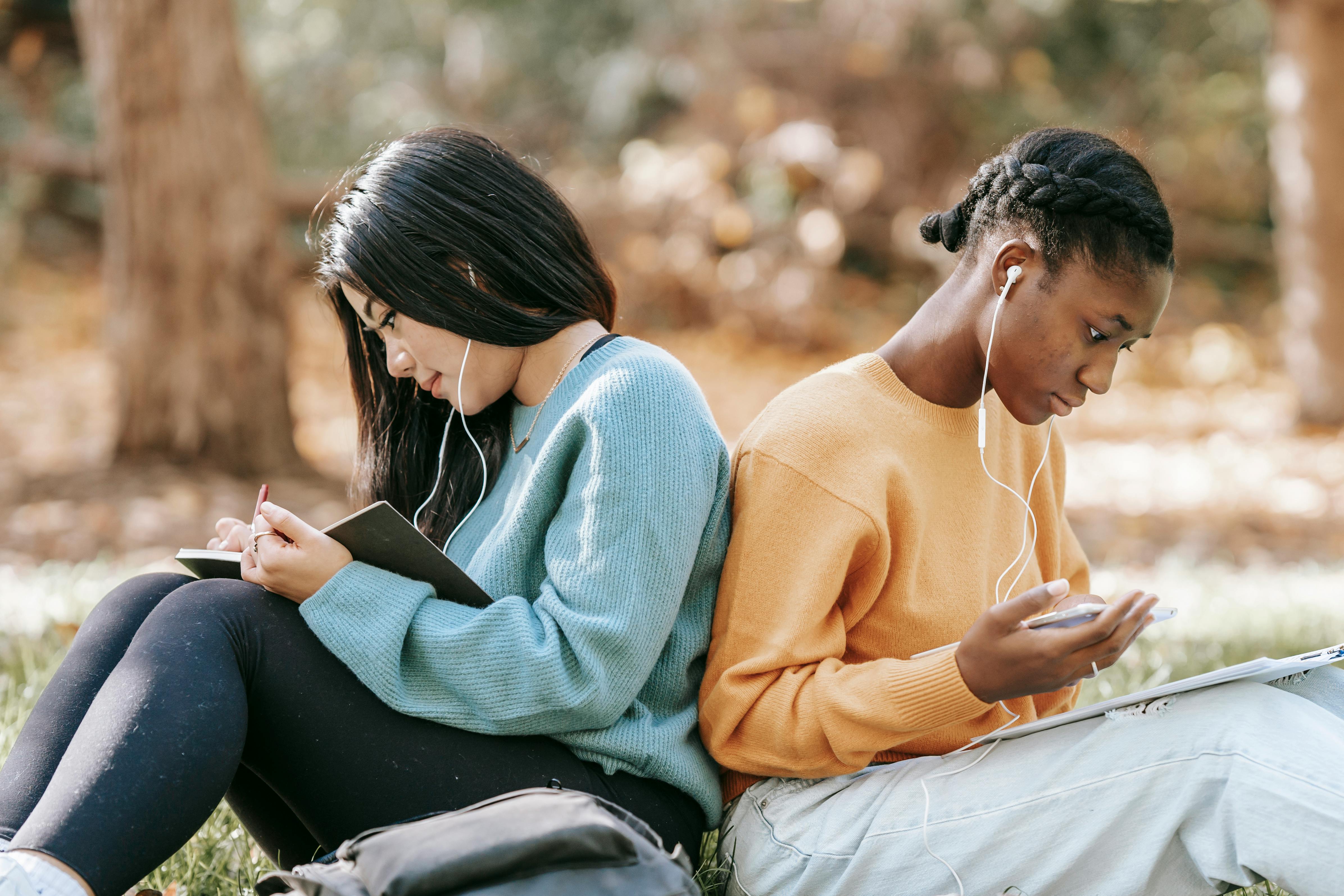 diverse young women studying with smartphone and notebooks