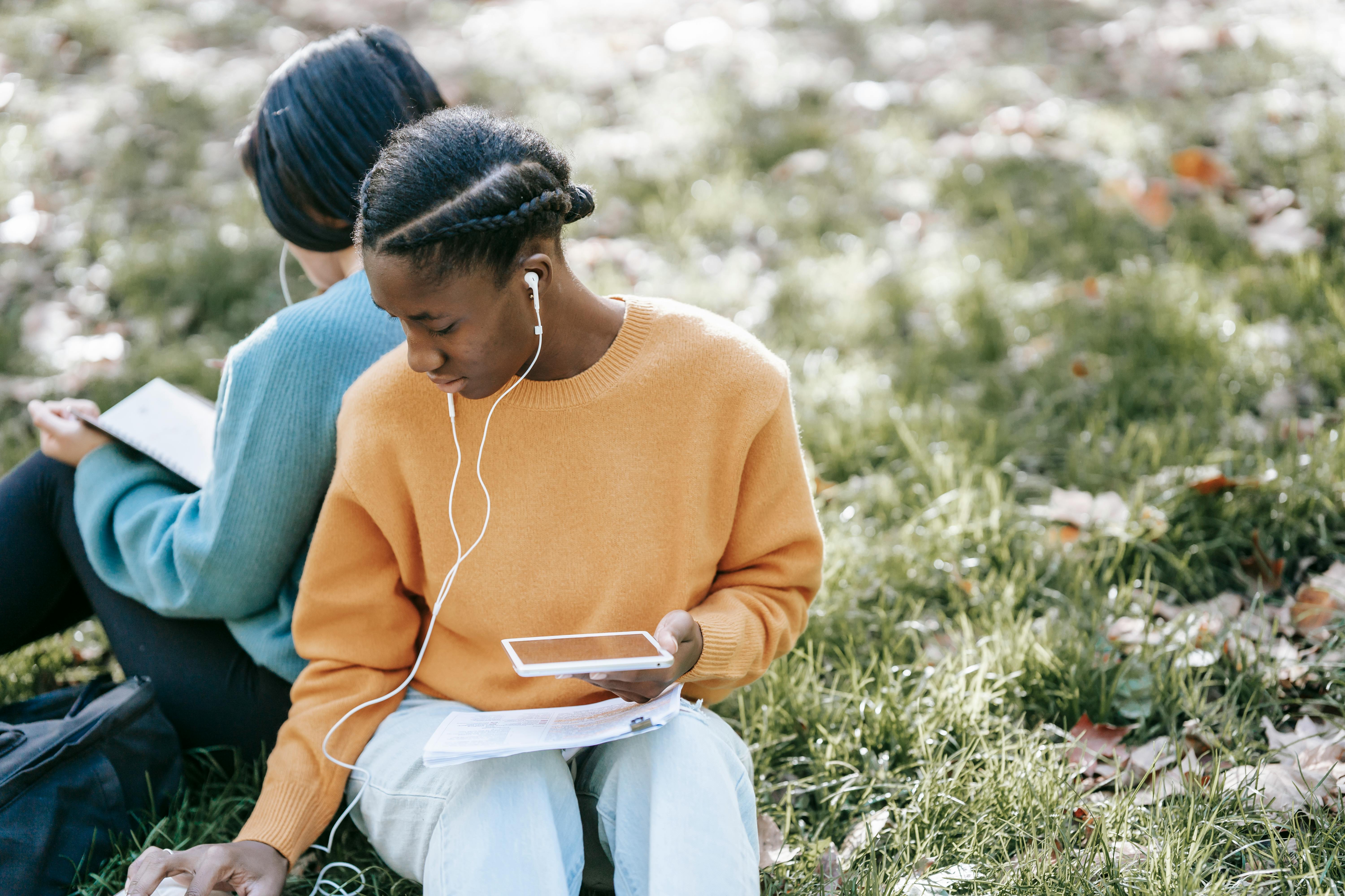 multiethnic women using tablet and reading in park