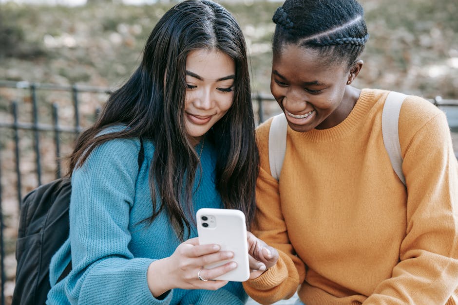 Cheerful multiethnic women browsing smartphone in park