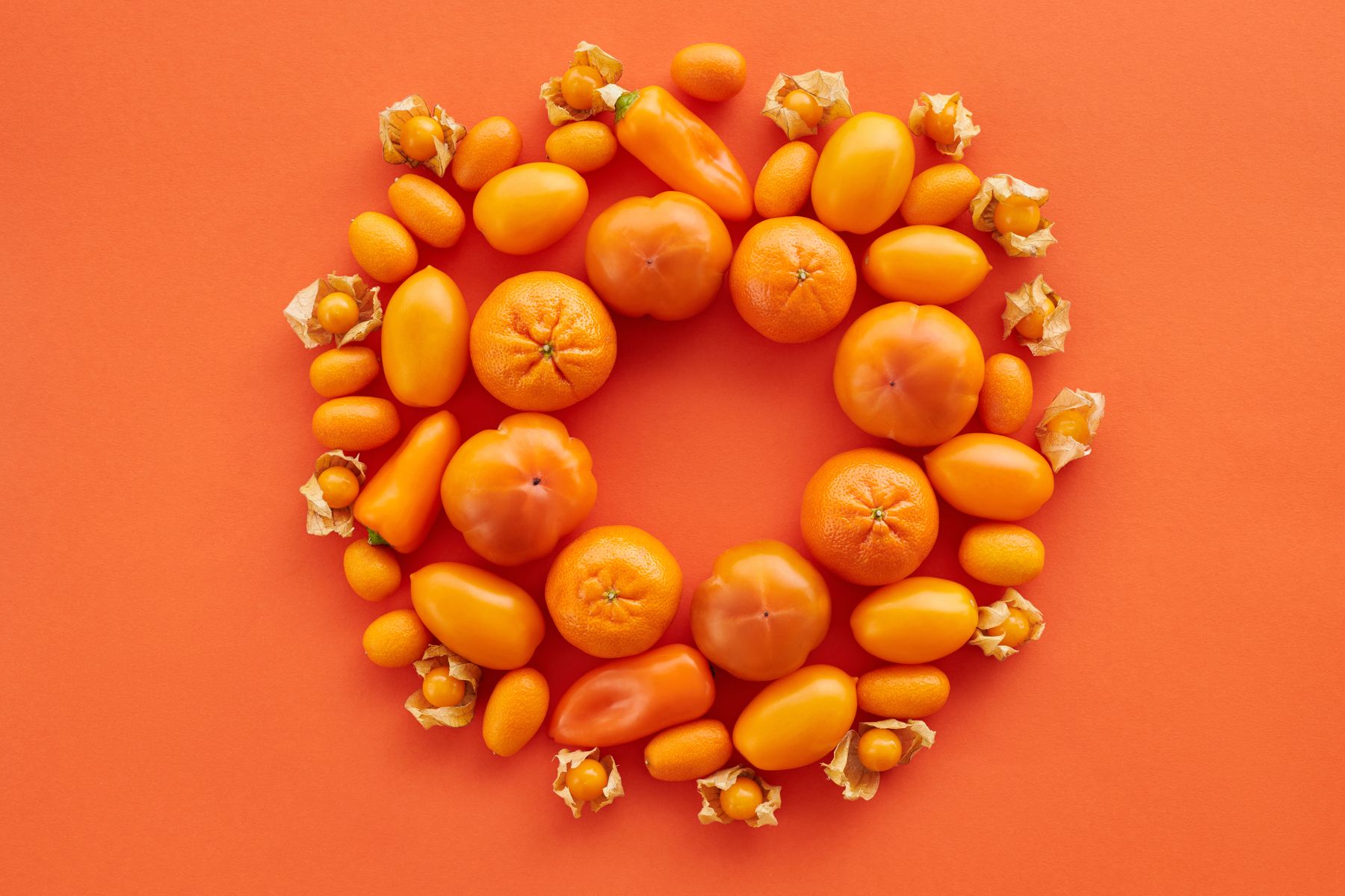 Overhead arrangement of citrus and peppers on a warm orange backdrop — photo by Vanessa Loring on Pexels