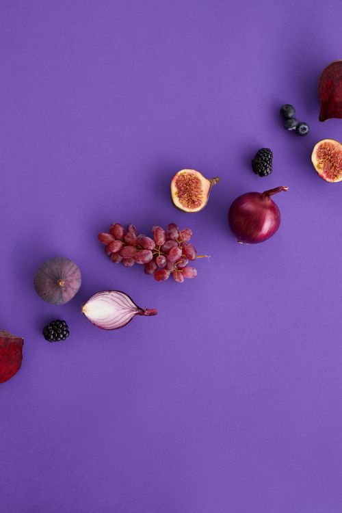 Free An artistic display of assorted fruits and vegetables on a purple background, perfect for healthy eating themes. Stock Photo
