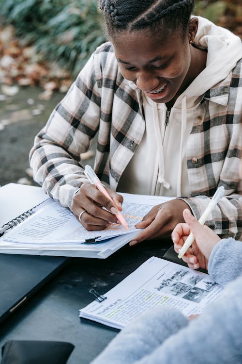 Free Crop multiracial students in casual clothes with pen taking notes while studying together Stock Photo