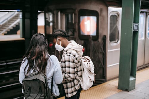 Faceless women in masks waiting for train