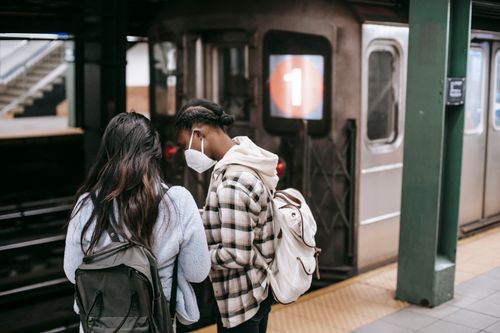Free Unrecognizable girlfriends in casual clothes with backpacks standing on platform of subway station and waiting for departure Stock Photo