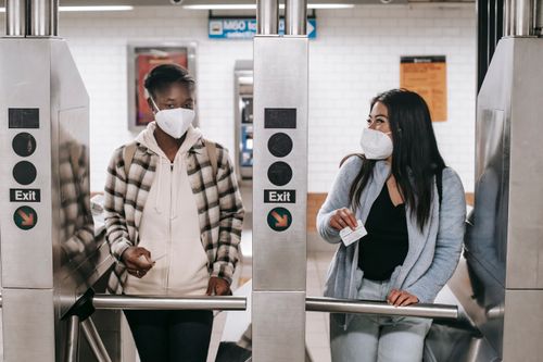 Free Young multiracial girlfriends in protective masks and casual clothes entering metro station with cards while talking with each other Stock Photo