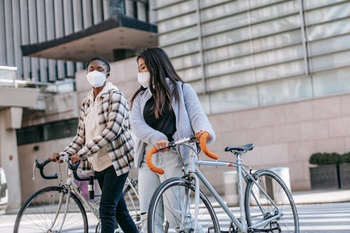 Mulher Em Camisa De Manga Comprida Listrada De Branco E Preto E Calça Preta Segurando Uma Bicicleta Preta Durante