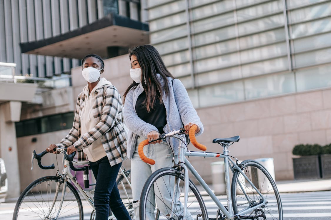 Young diverse women crossing road with bikes