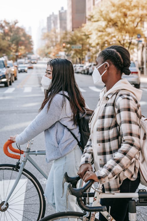 Multiracial friends crossing road with bicycles